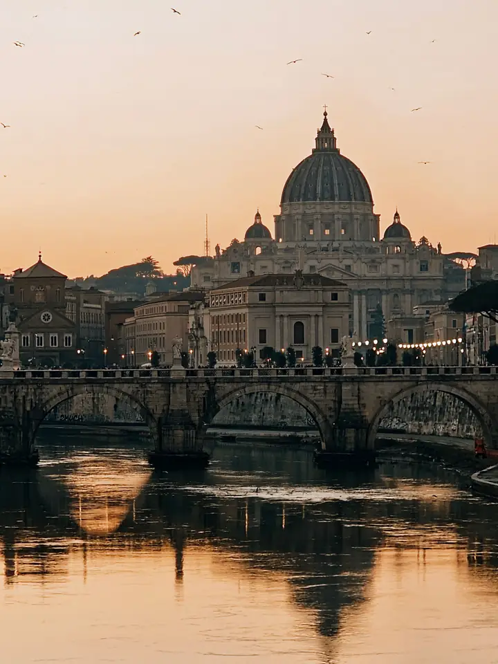 Petersdom-Kuppel im Abendlicht über dem Tiber
